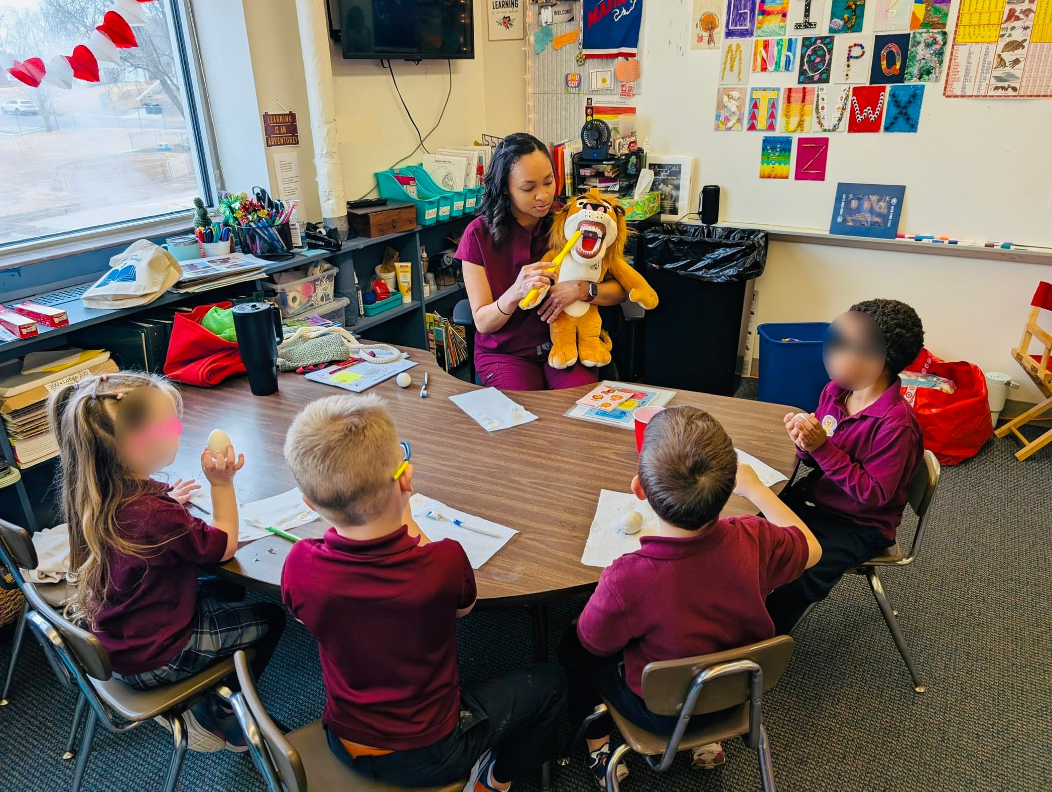 Dr. Mayo showing students how to brush with a lion puppet